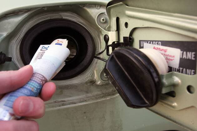 Steigende Benzinpreise: Hand steckt Euroscheine in den Benzintank