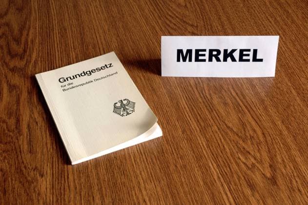 Dem Grundgesetz verpflichtet - Merkel-Namensschild neben einer Ausgabe des Grundgesetzes
