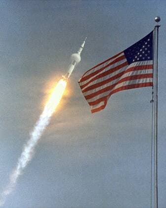 IMAGO History, Mondlandung der Apollo 11 am 20.07.1969 Bemannte Saturn V Rakete startet von Cape Canaveral hinter einer wehenden amerikanischen Landesfahne zur Apollo 11-Mission zum Mond  wax20050715101