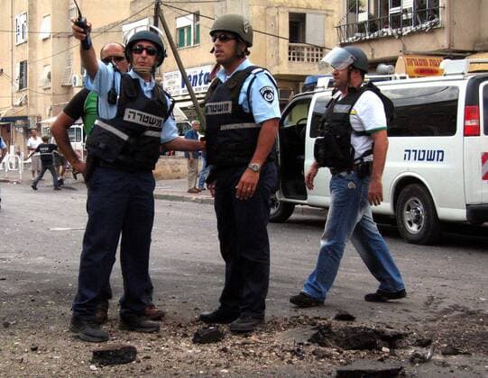 Israelische Polizisten versammeln sich in Nahariya an der Stelle, wo eine Katyusha-Rakete der libanesischen Hisbollah eingeschlagen ist - 