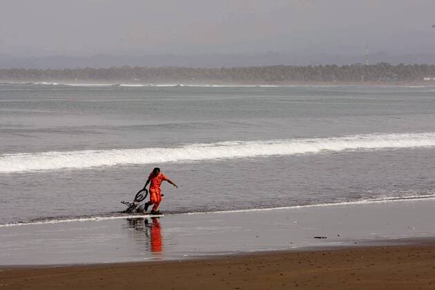 Rettungskraft zieht ein Fahrrad aus dem Meer nach dem Tsunami in Pangandaran auf Java - 