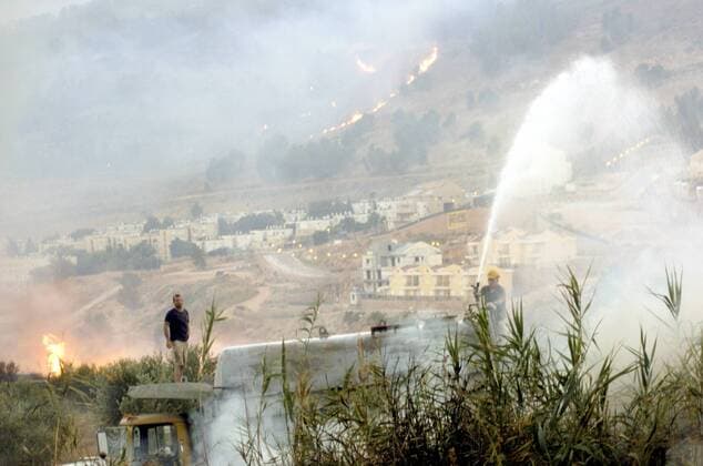 Israelische Zivilisten bekämpfen ausgebrochene Brände hervorgerufen durch Katjuscha-Raketen der Hisbollah in Kiryat Shemona im Grenzgebiet zu Libanon -  (JER2006072312)