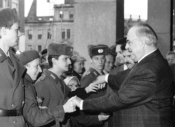 Bundeskanzler Helmut Kohl (vorn re., GER CDU) gibt Volkspolizisten die Hände während seines Besuches auf dem Altmarkt in Dresden