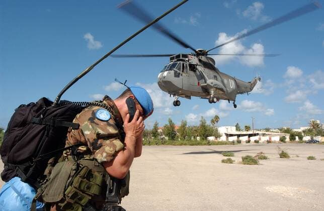 Italienischer Blauhelmsoldat der UN Friedenstruppe neben einem abfliegenden Helikopter in der Nähe von Tyre -  (bei2006090207)