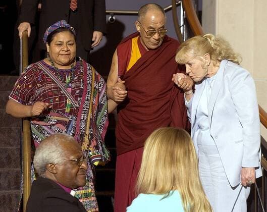 Betty Williams (re., IRL Mitbegründerin Community of Peace People) küsst zur Begrüßung die Hand von dem 14. Dalai Lama (CHN Religiöses und politisches Oberhaupt der buddhistischen Tibeter) neben Politikerin Rigoberta Menchu Tum (li., GUA), Desmond Tutu (unten li., RSA Erzbischof von Kapstadt) und Menschenrechtsaktivistin Jody Williams (USA Sprecherin der Internationale Kampagne für das Verbot von Landminen) anlässlich ihrer Ankunft zur 10. PeaceJam Konferenz an der University of Denver in Denver -  (den2006091527)