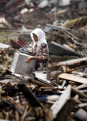 Indonesierin birgt im Regen ihre Habseligkeiten aus den Trümmern ihres ehemaligen Wohnhauses nach dem verheerenden Tsunami in Banda Aceh -  (wax20050119108)