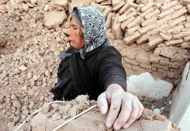 Einheimische Frau steht fassungslos in den Trümmern eines von einem Erdbeben zerstörten Wohnhauses in Bam im Iran -  (irn2003122703)