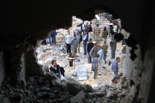 Palästinenser stehen neben einem riesigen Einschussloch in einer Hauswand nach einem israelischen Angriff auf Rafah -  (gaza2004031805)
