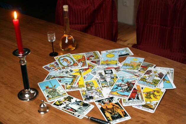 Tarotkarten auf einem Tisch mit brennender Kerze und einem Gläschen Likör