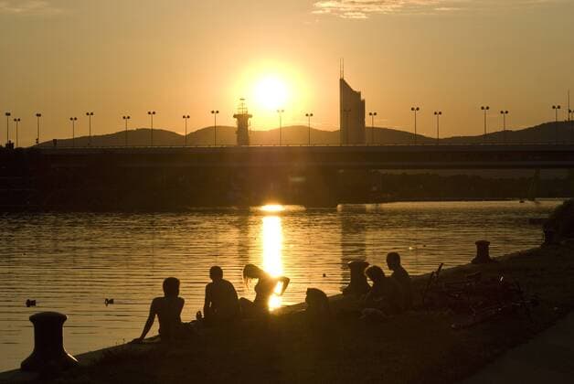 Junge Leute genießen den Sonnuntergang am Ufer der Neuen Donau in Wien