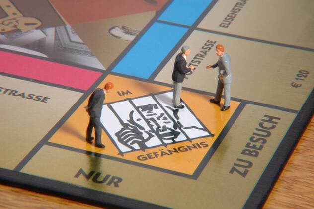 Betrügerisches Spiel - Managerfiguren auf dem Gefängnisfeld eines Monopoly-Spiels
