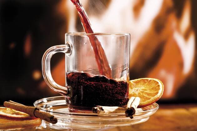  Glas Glühwein mit Zimtstangen und getrockneter Orangenscheibe vor Kaminfeuer - ibxodh00769510