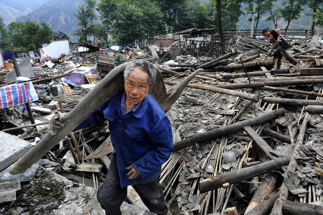 Mann trägt einen Pflug - Suche nach Brauchbaren in den Trümmern nach dem Erdbeben vom 12. Mai in Yingxiu, Provinz Sichuan - China 