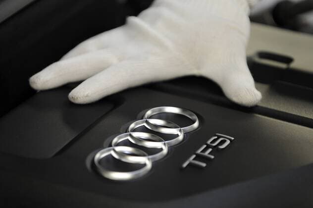Hand eines Mitarbeiters in weißem Handschuh auf einem Motor eines A6 im Prüfzentrum des Audi-Werks in Neckarsulm
