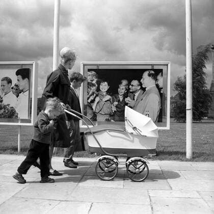Junge Mutter mit Kinderwagen und ihren Kindern vor einem Foto von Walter Ulbricht in Berlin-Ost
