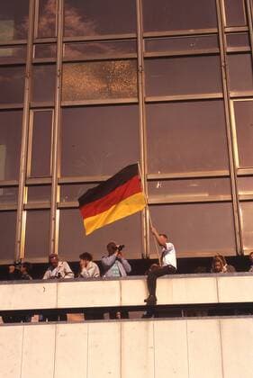 Besucher schwenkt die Deutschlandflagge am Palast der Republik am Tag der Deutschen Einheit in Berlin