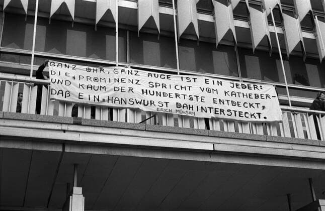 Teilnehmer der ersten oppositionellen Protestkundgebung enthüllen ein Transparent mit einem Erich Mühsam-Zitat während einer Demonstration auf dem Kaufhaus auf dem Alexanderplatz in Berlin