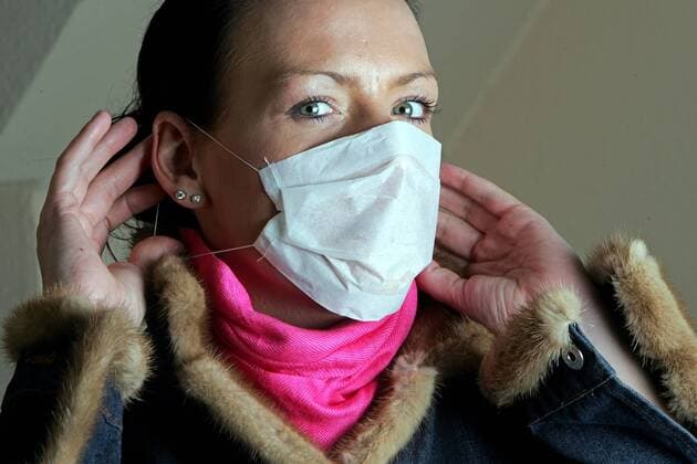 Junge Frau legt einen Mundschutz an. - MODEL RELEASED