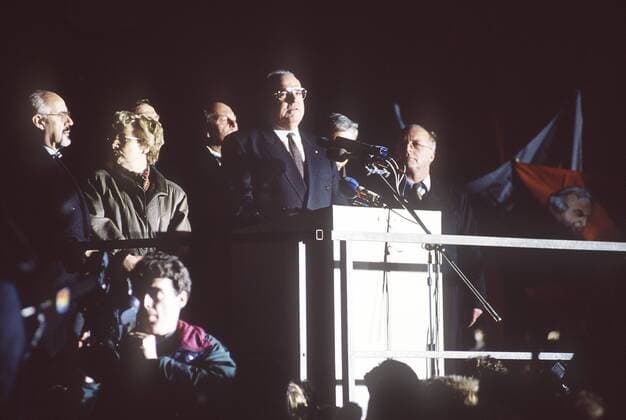 Bundeskanzler Helmut Kohl, CDU, spricht vor Menschen in Dresden, rechts Bundesarbeitsminister Norbert Blüm, Kohl und seine Delegation stehen in hellem Scheinwerferlicht,19.12.1989.