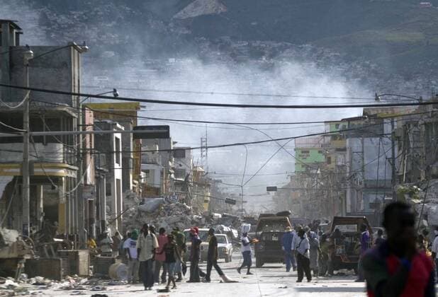 (100117) -- PORT-AU-PRINCE, Jan. 17, 2010 (Xinhua) -- People walk past the collapsed buildings in Port-au-Prince, capital of Haiti, Jan. 16, 2010. (Xinhua David de la Paz) (lyi) (3)HAITI-QUAKE-STREET 