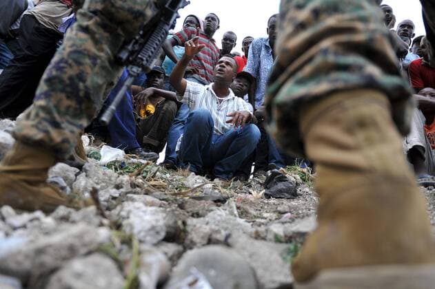 A Haitian man talks to Marines with the 22nd Marine Expeditionary Unit in Leogand, 25 miles outside of Port-au-Prince, January 20, 2010. The U.S. military has begun Operation United Response and has begun delivering aid to Haiti following a 7.0 magnitude earthquake that stuck the country.  HAI20100120302