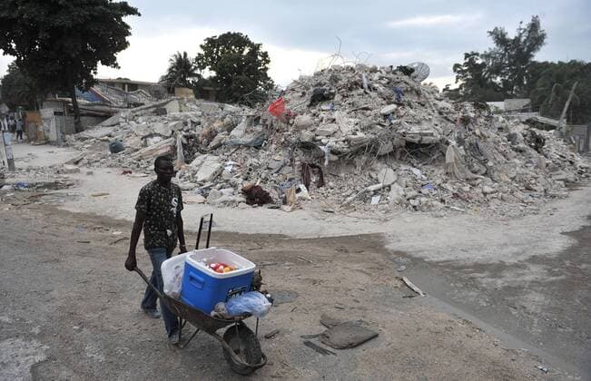 A man pushes a wheel barrow past earthquake rubble in Port-au-Prince, Haiti on January 26, 2010. Haiti continues to suffer after a 7.0 magnitude earthquake devastated the country on January 12.  HAI201001256317