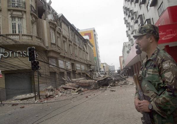 An armed military officer stands guard on street filled with debris in Concepcion, Chile on March 1, 2010, following an 8.8 magnitude earthquake that struck the country on February 27.  CHL20100301730