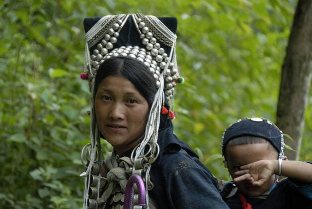 IMAGO Cultures of the world, Akha Volk in Laos Portrait, Frau der Akha Nuqui Ethnie, Mutter mit Kind, traditionelle Kleidung, Kopfschmuck, mit silbernen Perlen verzierte Haube, bei Ban Chakhampa, Distrikt und Provinz Phongsali, Laos, Südostasien, Asien iblsau01483453