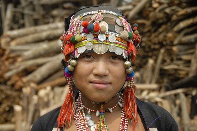 IMAGO Cultures of the world, Akha Volk in Laos Portrait, Mädchen der Akha Eupa Ethnie lächelt, traditionelle Kleidung, Haube als Kopfbedeckung mit bunten Bommeln Ketten und Silbermünzen, Ban Yangpa, Distrikt Samphan, Provinz Phongsali, Laos, Südostasien, Asien iblsau01508093