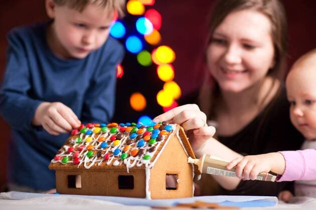 Familie schmückt Lebkuchenhaus am Weihnachtsabend. Konzentrieren Sie sich auf Haus - McPSHA
