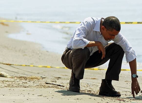 U.S. President Barack Obama picks up balls of tar while touring the beach on May 28, 2010 in Port Fourchon, Louisiana. The oil spill resulting from the Deepwater Horizon disaster now officially ranks as the worst in U.S. history.  WAX20100528713