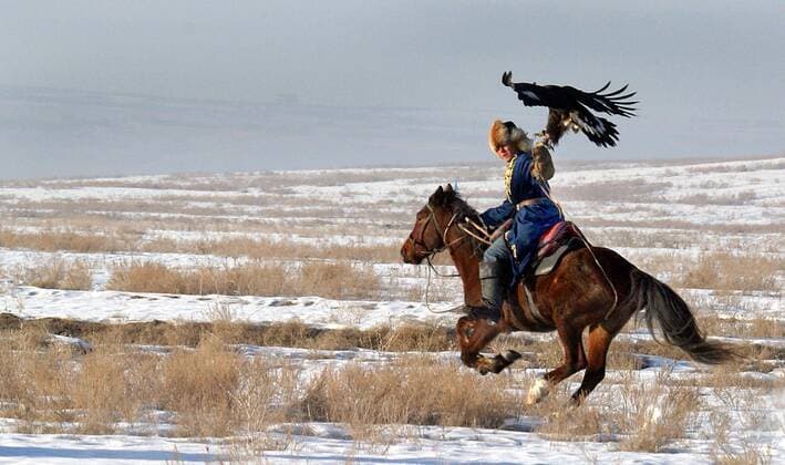 ALMATY REGION, KAZAKHSTAN. Hunter with his bird rides a horse during Kazakhstan s National Competitions of Berkutchi (Golden-Eagle hunters). Kazakhs are renowned for their unique and extraordinary skill in using Golden Eagles to hunt small prey.  424959