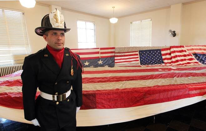 20 Jahre Anschläge vom 11. September: Gedenkkultur in den USA St. Louis firefighter Brian Hesse stands guard at the National 9 11 Flag at the Soliders Memorial in St. Louis on October 11, 2010. The 30-foot American flag, destroyed when the World Trade Center buildings collapsed on September 11, 2001, is currently traveling around the country as part of a restoration effort, sponsored by The New York Says Thank You Foundation. The foundation wants to empower local service heroes in all 50 states with the privildge of stitching the flag back to its original 13-stripe format. The New York Says Thank You Foundation wants to make the flag whole again by the 10th year anniversary of 9 11. It will become part of the permanent collection of the National September 11 Memorial Museum being built at the World Trade Center site.  SLP2010111111