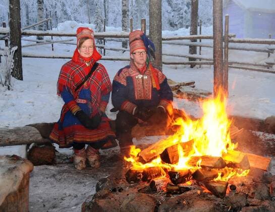 (101217) -- ROVANIEMI, Dec. 17, 2010 (Xinhua) -- A Sami couple sit near a bonfire in Lappland, a famous tourist resort of north Finland, Dec. 15, 2010. Riding a reindeer sledge for tour is popular among tourists who come to the town in the Arctic Circle in winter. (Xinhua Zhao Changchun) (wjd) FINLAND-REINDEER SLEDGE-TOURISM 