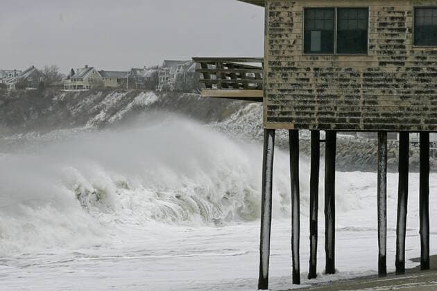 Waves break in front of a house on stilts at Peggotty Beach in Scituate, Massachusetts at the tail end of an overnight blizzard on December 27, 2010. Parts of Massachusetts received over a foot and a half of snow from the storm and left many homes without power.  BOS2010122704