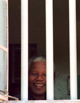 IMAGO History, Ende der Apartheid in Südafrika: 1990-1994 Robben Island CAPE TOWN, SOUTH AFRICA - 1995: President Nelson Mandela during a visit to Robben Island and his former cell looks through the bars at the freedom on the outside. ( Gallo0005674