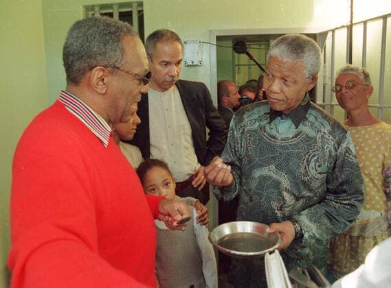 IMAGO History, Ende der Apartheid in Südafrika: 1990-1994 Robben Island CAPE TOWN, SOUTH AFRICA - 1997: Nelson Mandela (2nd R) and Bill Cosby (L) in Nelson Mandela s old prison cell. 1997. Right: Cosby s wife Camille Gallo0005700