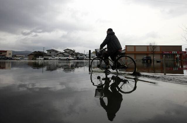 (110315) -- ISHINOMAKI, March 15, 2011 (Xinhua) -- A man rides through water in the quake-hit area of Ishinomaki city, Miyagi Prefecture, Japan, March 15, 2011. (Xinhua Ren Zhenglai) (zcc) JAPAN-QUAKE 