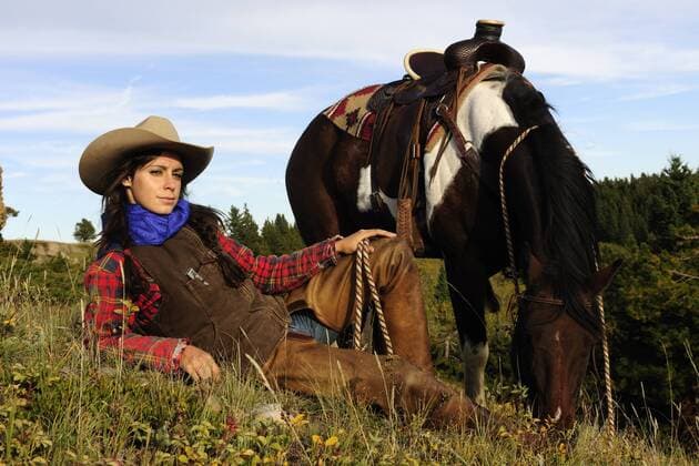 Cowgirl liegt im Gras, daneben steht das Pferd, Saskatchewan, Kanada ibltps01893821