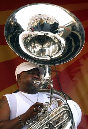 With the crowd reflected in his instrument, Julius McKee of the Dirty Dozen Brass Band plays the tuba at the New Orleans Jazz and Heritage Festival in New Orleans, May 1, 2011.  NOP2011050111