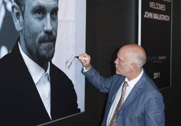 Schauspieler John Malkovich signiert ein im Gasteig aufgehängtes Malkovich-Porträt Verleihung des CineMerit Awards Filmfest München 27.06.2011