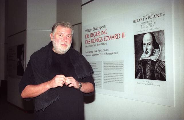 Regisseur Frank-Patrick Steckel neben einem Bild von William Shakespeare im Schauspielhaus Köln