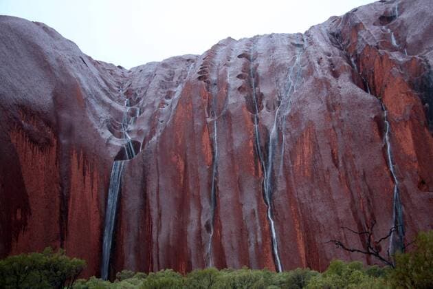 Der Der Uluru , auch Ayers Rock , am Montag (17.08.2009) im Northern Territory Australien bei Regen . Er ist ein an der Oberfläche befindlicher Teil einer großen unterirdischen Gesteinsschicht in der zentralaustralischen Wüste .