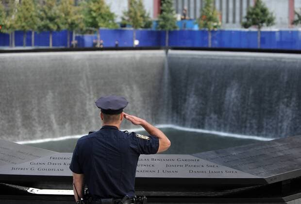 20 Jahre Anschläge vom 11. September: Gedenkkultur in den USA A New York City police officer salutes at the North Pool of the 9 11 Memorial during the singing of the National Anthem during the tenth anniversary ceremonies at the site of the World Trade Center September 11, 2011, in New York.  NYC0916