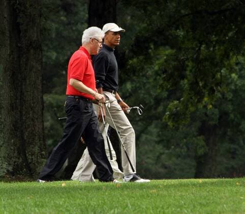 Former U.S. President Bill Clinton (L) and U.S. President Barack Obama (R) chat after completing the first hole during a golf game at Joint Base Andrews, Maryland, on September 24, 2011.  WAX2011092403