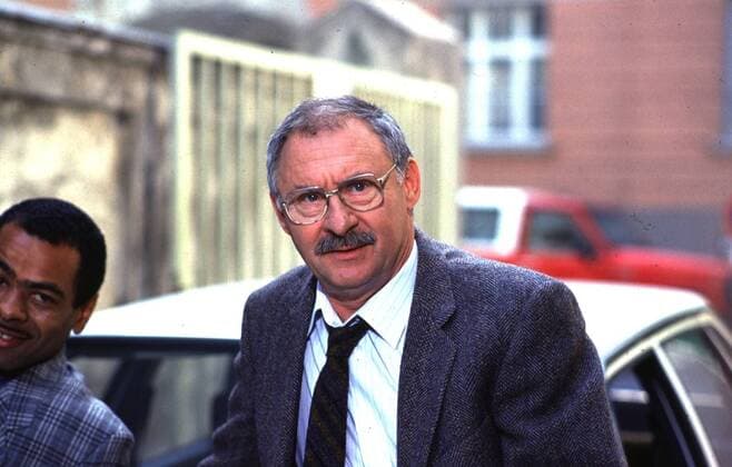Der Alte (ZDF) Rolf Schimpf (re.) mit Charly M. Huber 09 85 wie Schauspiel TV Fernsehen Serie Krimi Mann Szene Filmszene draußen stehend Polizei Auto Kennzeichen Haus Gebäude Straße aufstützend lächelnd halb quer
