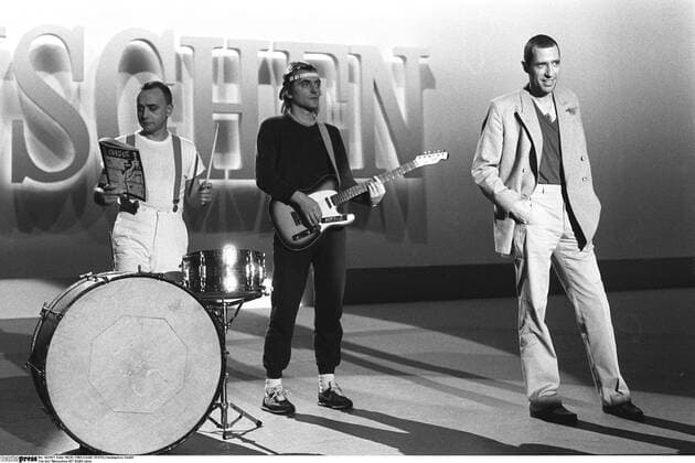 Trio bei Menschen 82 01 83 stroe Peter Behrens, Gert Krawinkel und Stephan Remmler (v.l.) von der Band Trio zu Gast in der Show Menschen 82 am 8. Januar 1983 in Berlin Mann Männer deutsch Musik Musiker Pop Gruppe Popgruppe Band Trio Gesang Neue Deutsche Welle NDW Auftritt leger Schlagzeug Gitarre Instrument Instrumente spielen spielend stehend singen singend Hosenträger Kopfbedeckung Kappe Hut Mütze Anzug Zeitung lesend lesen neutral lächeln lächelnd Fernsehstudio Studio Kulisse Bühne Fernsehauftritt Fernsehsendung Fernsehshow Sendung Querformat quer ganz sw s w schwarz weiß schwarzweiß schwarz-weiß schwarz weiß