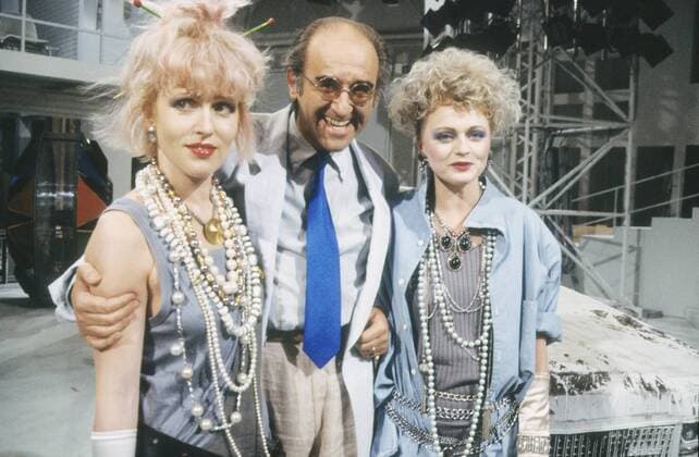 Alfred Biolek mit den Schwestern Annette (li.) und Inga Humpe in Mensch Meier 06 85 vZ Mann Moderator Moderation TV Fernsehen Brille dunkelhaarig kurzhaarig Halbglatze seriös Jackett Krawatte halb quer stehend TV-Studio Kulisse Dekoration Bühne lächelnd umarmend Schmuck Kette Ketten