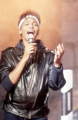 Whitney Houston (Sängerin, Schauspielerin) 06 85 wie Whitney Houston im Juni 1985 in Peter Illmann Treff (P.I.T.), ARD Frau TV Fernsehen Schauspiel Musik Gesang Sängerin Pop USA Amerika amerikanische leger dunkelhaarig kurzhaarig dunkelhäutig Stirnband Lederjacke Soul american female singer hoch halb stehend singend gestikulierend