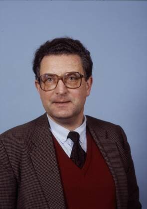 Gerhart Baum (FDP-Politiker) 03 86 - Mann Politik Partei FDP stellvertretender Bundesvorsitzender der FDP dunkelhaarig kurzhaarig Locken Wellen Brille seriös Jackett Hemd Krawatte Pullunder Pullover stehend Studio vor Wand Freisteller halb hoch fragend lächelnd